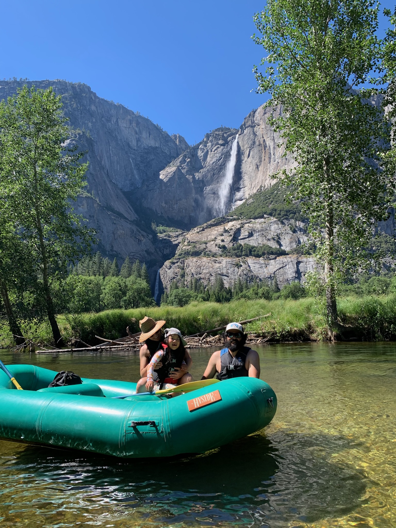 Family in a raft near a waterfall during an outdoor trip